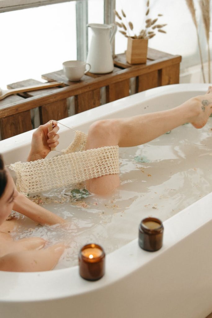 A serene moment of relaxation in a bathtub surrounded by warm candlelight indoors.